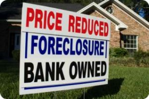 real_estate_investments Price reduced bank owned foreclosure sign in front of home